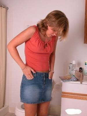 Amateur girl Karen hikes her denim skirt in the bathroom to expose her panties on modelies.com