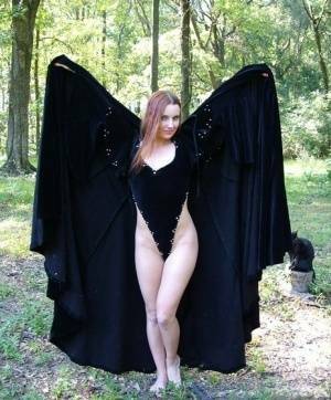 Redhead amateur Amber Lily models nude in a forest draped in a black cape on modelies.com