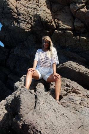 Blonde amateur Sweet Susi exposes her tits and ass on a rocks by the sea on modelies.com