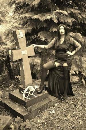 Goth girl Barby Slut bares her big tits and twat atop a casket in the woods on modelies.com