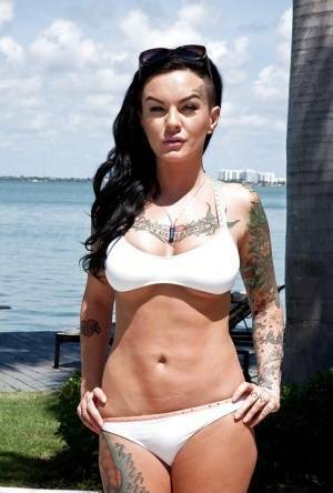 Tattooed whore Lolo Luscious exposing big hooters in swimming pool on modelies.com